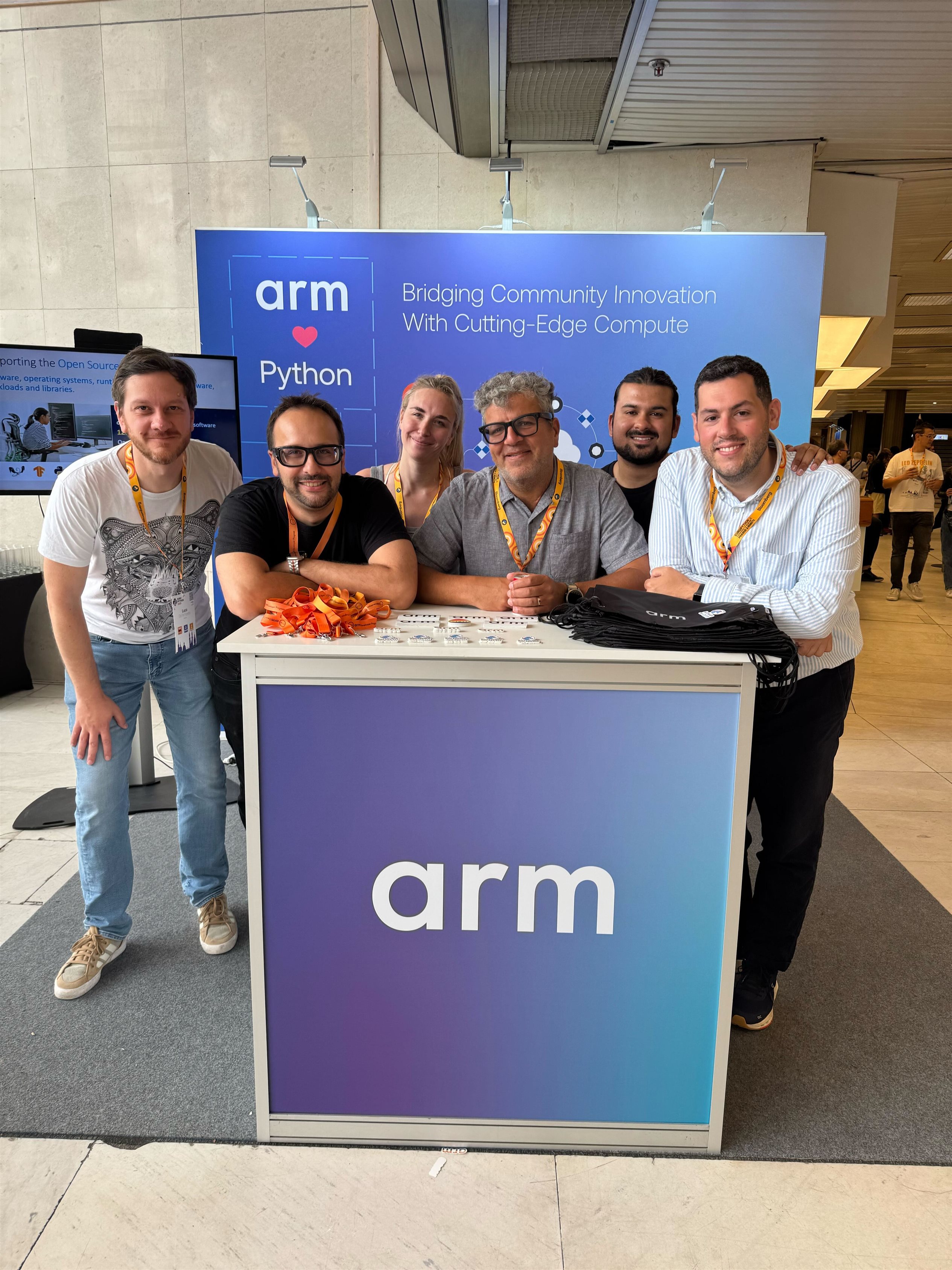 The Arm Software Communities team standing at their booth at the EuroPython 2025 event